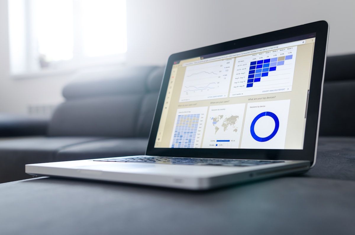A laptop open on a sofa showing charts and a world map